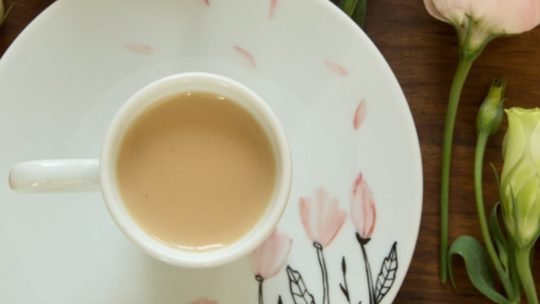 Xícara de chá com leite servida em ambiente acolhedor