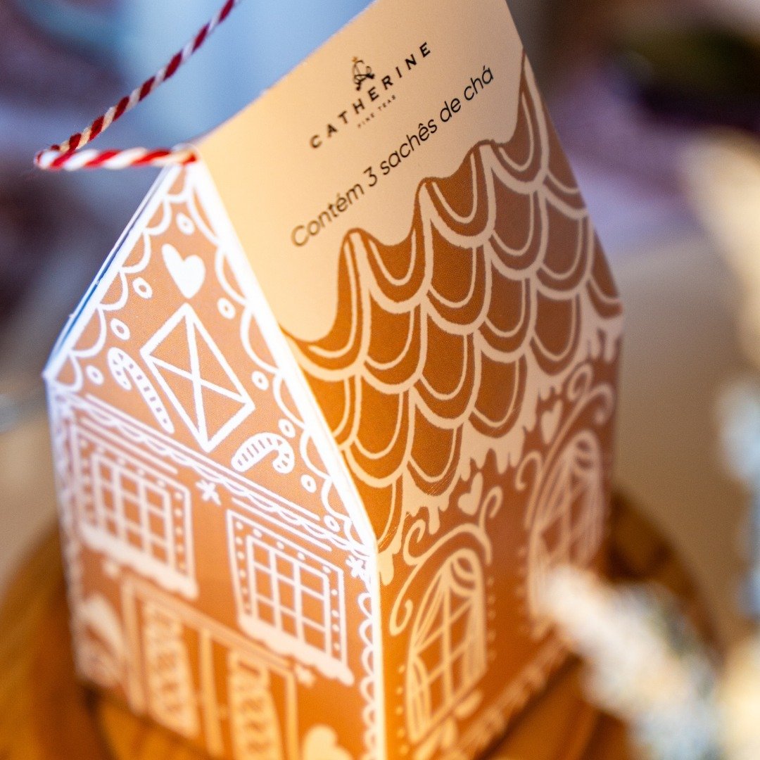 Detalhe frontal da Gingerville House Catherine Fine Teas com cordão trançado vermelho e branco e ilustrações inspiradas em casas de biscoito natalinas.