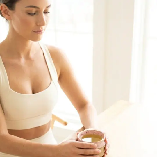 Mulher serena segurando xícara de chá verde Catherine Fine Teas durante momento de pausa e jejum intermitente.