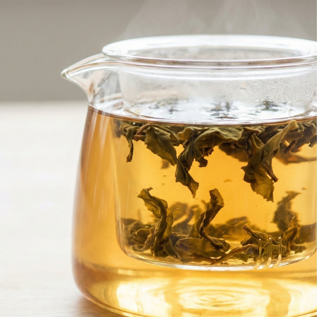 Bule de vidro com folhas soltas de chá em processo de infusão sob luz natural