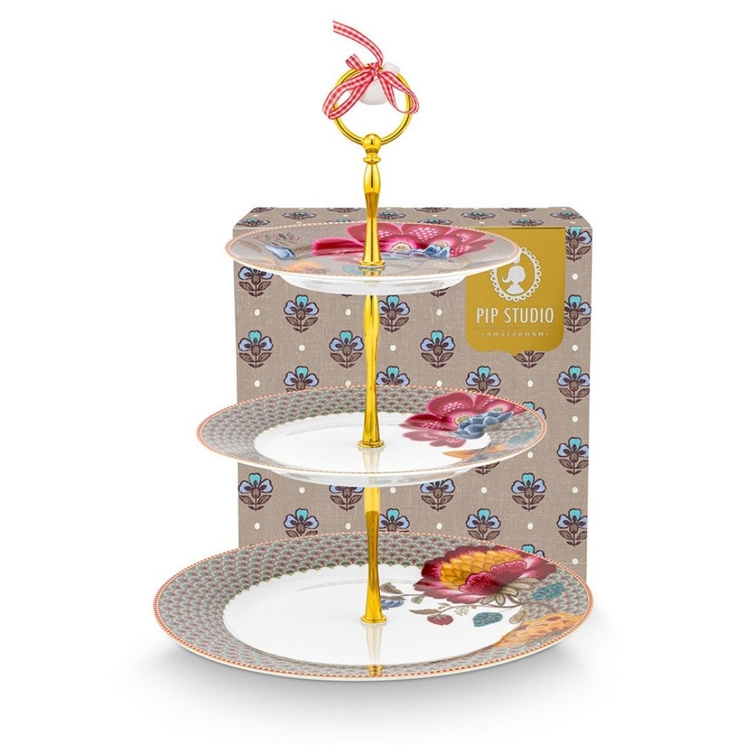 Suporte de três andares para doces em porcelana cáqui com estampas florais da coleção Blooming Tales Pip Studio e detalhes em ouro, posicionado no centro de uma mesa de chá.